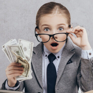 young business kid shocked, holding a fist full of money